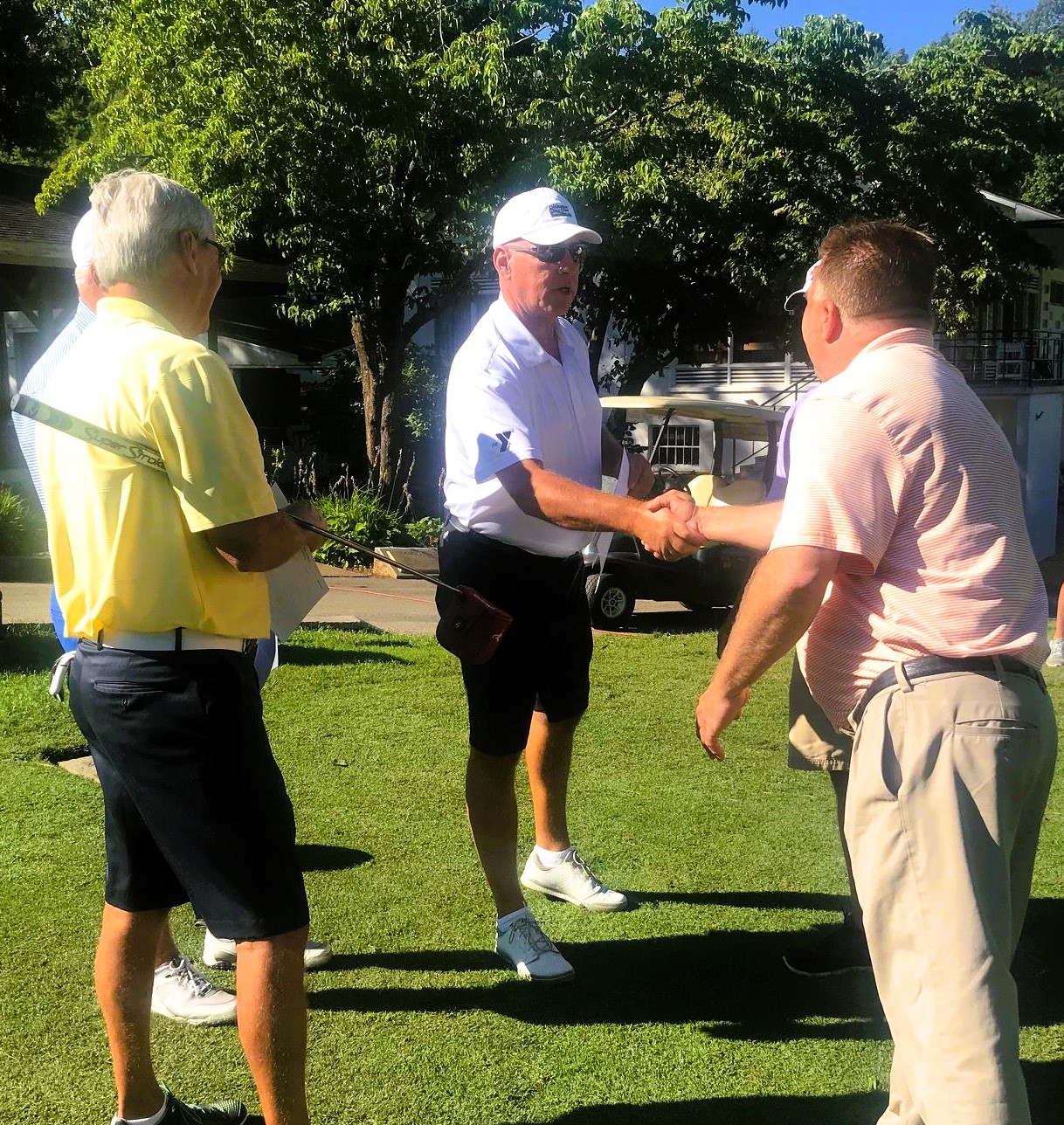 three gentlemen on a putting green.